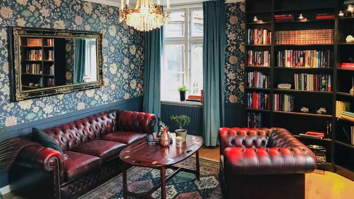 Ein Wohnzimmer mit roten Ledersofas und Bücherregalen