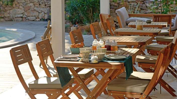 Eine Reihe von Holztischen und Stühlen auf einer Terrasse