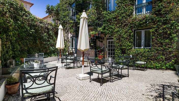 Eine Terrasse mit Tischen und Stühlen und weißen Regenschirmen