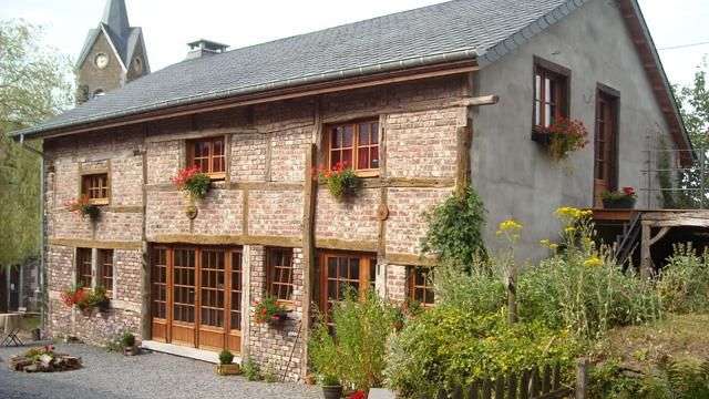 Ein Backsteinhaus mit vielen Fenstern und einer Kirche im Hintergrund .