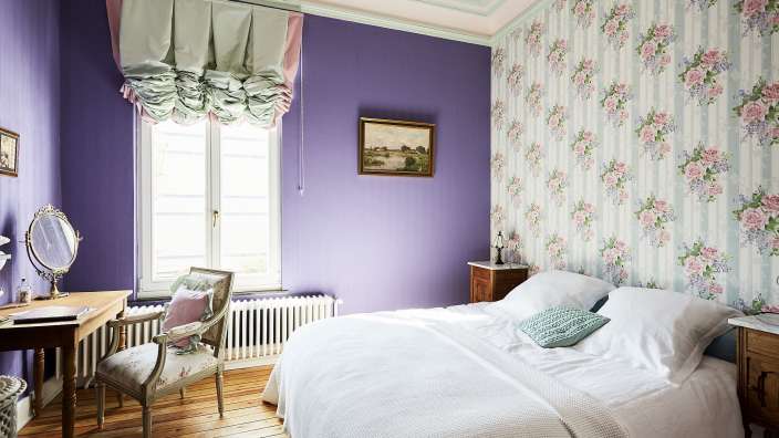 Ein Schlafzimmer mit lila Wänden und Blumentapeten