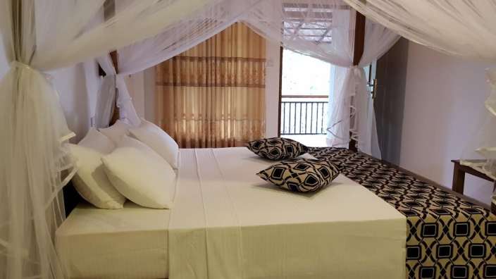 Ein Himmelbett mit weißen Bettwäschen und schwarzen Kissen