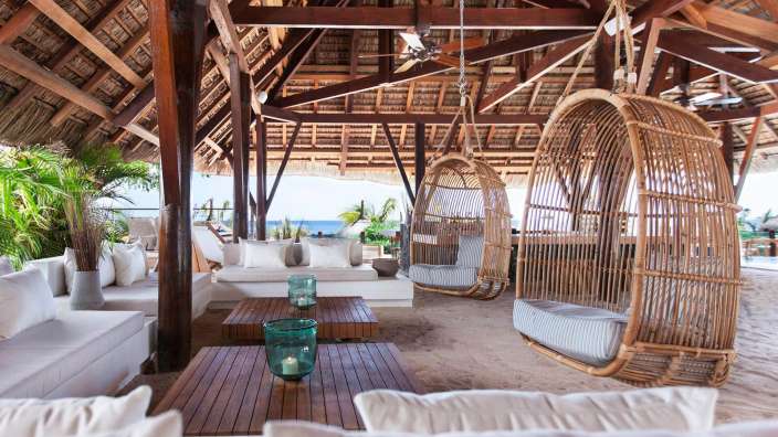 Ein Wohnzimmer mit weißen Möbeln und hängenden Stühlen