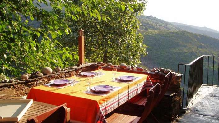 Ein Tisch mit Tellern und Gläsern auf einem Balkon mit Blick auf die Berge