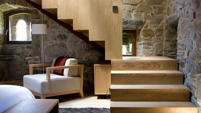 Eine Holztreppe mit einem Stuhl und einer Lampe darunter