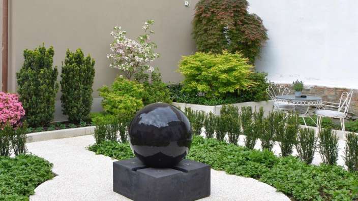 Ein Garten mit einem Tisch und Stühlen und einem schwarzen Ei