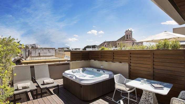 Ein Whirlpool auf einer Terrasse neben einem Tisch und Stühlen