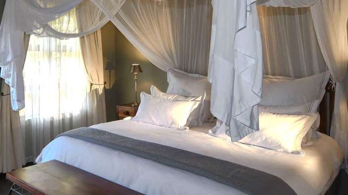 Ein Schlafzimmer mit einem Himmelbett und weißen Vorhängen