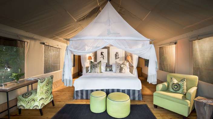 Ein Schlafzimmer mit Himmelbett und grünen Stühlen