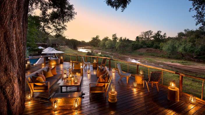 Ein Deck mit Möbeln und Kerzen und einem Fluss im Hintergrund