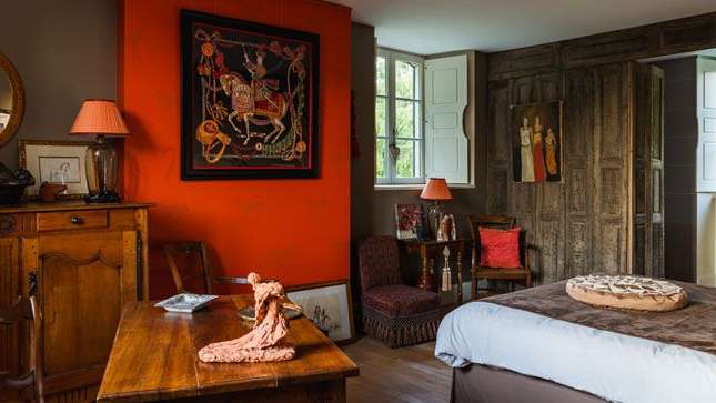 Ein Schlafzimmer mit einem großen Gemälde an der orangefarbenen Wand