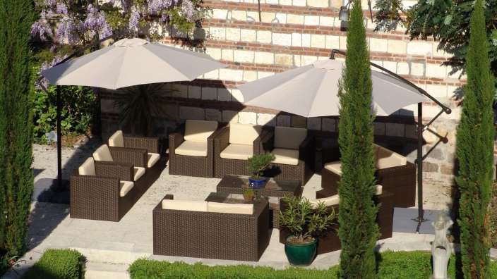 Eine Terrasse mit Möbeln und Regenschirmen vor einer Backsteinmauer