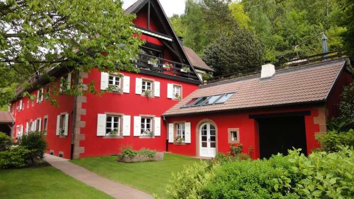 Ein rotes Haus mit weißen Fensterläden und einem Dachfenster