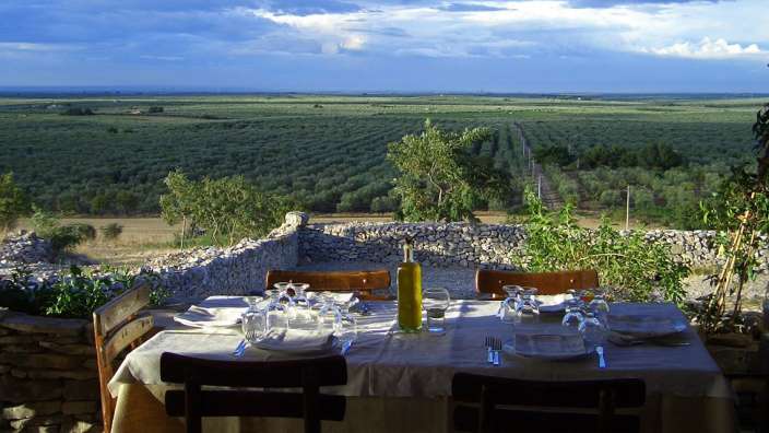 Ein Tisch mit Gläsern und Tellern und einer Flasche Olivenöl darauf