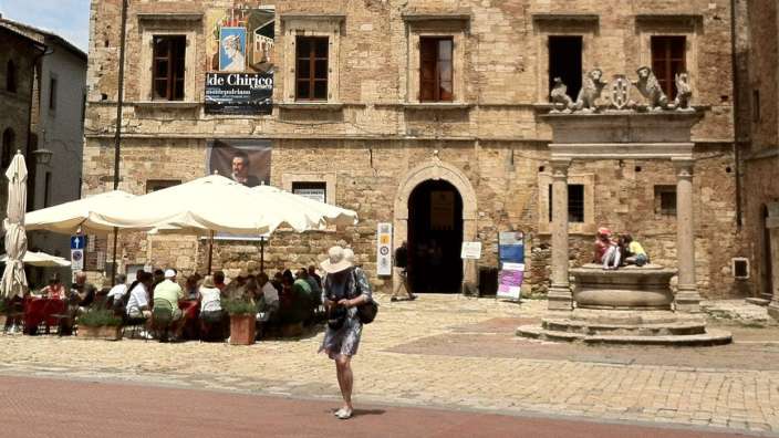 Eine Frau geht vor einem Gebäude mit einem Schild darüber