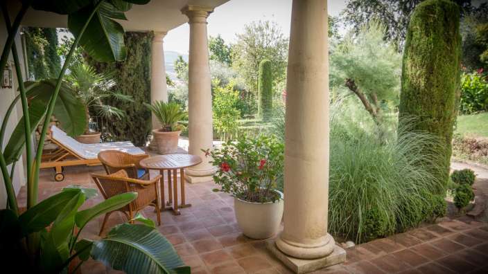 Ein Tisch und Stühle stehen auf einer Terrasse mit Steinsäulen