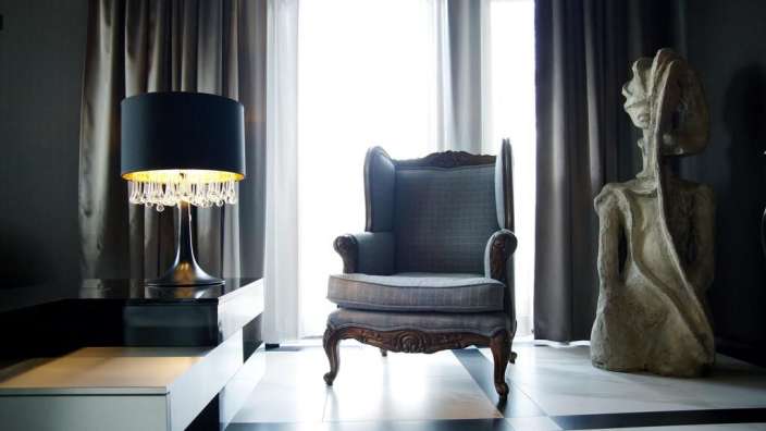 Ein grauer Stuhl steht in einem Raum neben einer Lampe