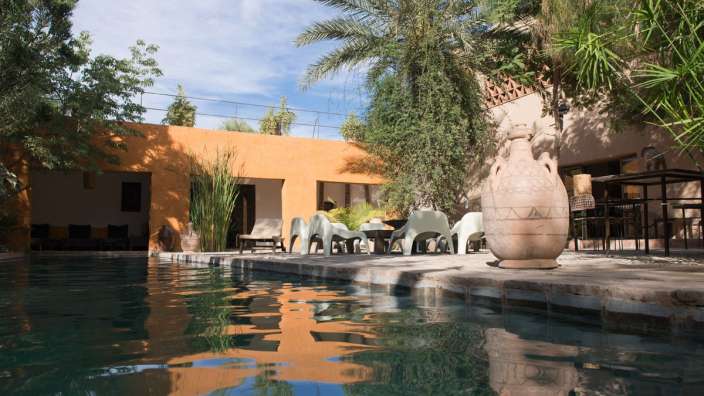 Ein Swimmingpool mit einem Tisch und Stühlen im Hintergrund