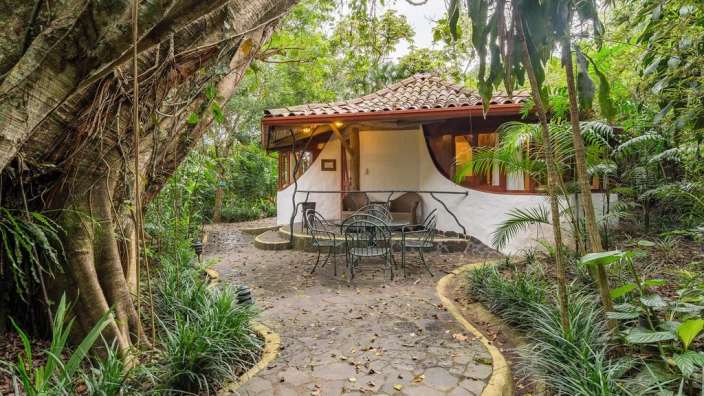 Ein kleines Haus im Dschungel mit einem Tisch und Stühlen