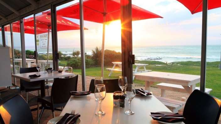 Tische und Stühle in einem Restaurant mit Blick auf den Ozean