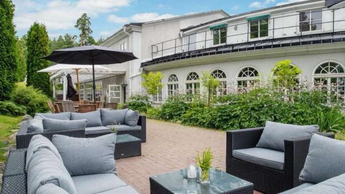 Eine Terrasse mit Möbeln und Sonnenschirmen vor einem großen Gebäude