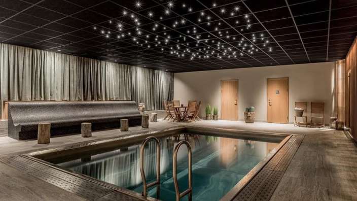 Ein Swimmingpool in einem Raum mit einem Tisch und Stühlen