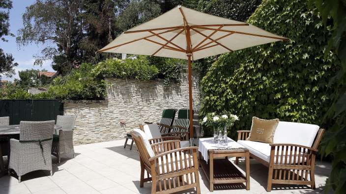 Eine Terrasse mit Möbeln und einem Regenschirm mit der Aufschrift hiphotels