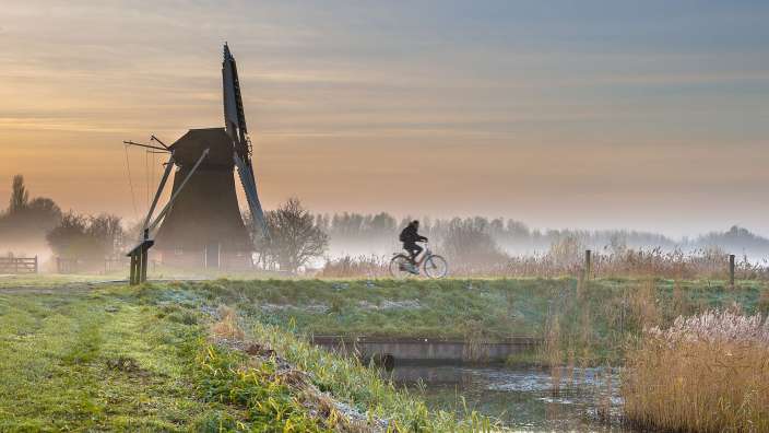 Eine Person fährt mit einem Fahrrad in der Nähe einer Windmühle