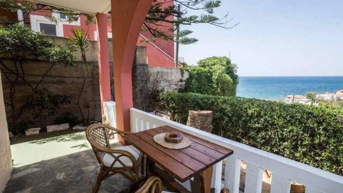 Ein Tisch und ein Stuhl auf einem Balkon mit Blick auf das Meer