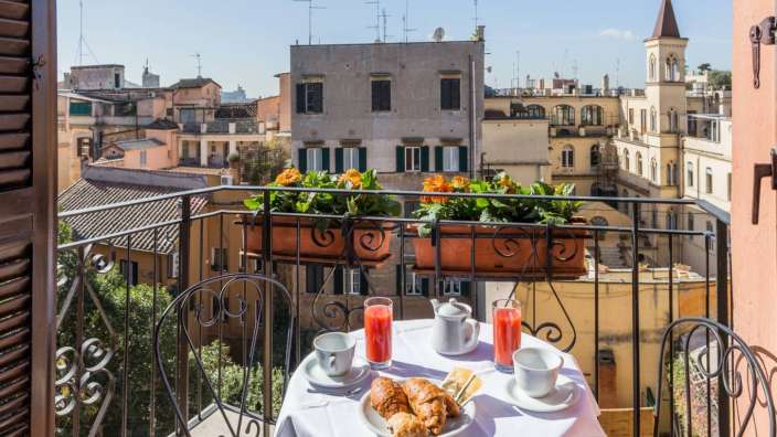 Ein Tisch mit einem croissant und einem Glas Saft auf einem Balkon
