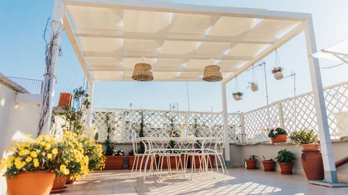 Ein weißer Tisch und Stühle unter einer weißen Pergola