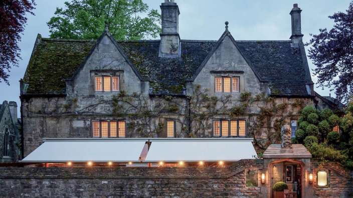 Ein großes Steinhaus mit einem weißen Vordach und vielen Fenstern