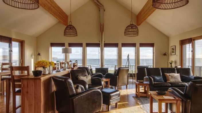 Ein Wohnzimmer mit vielen Fenstern und einem Blick auf das Meer