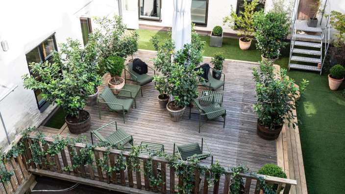 Ein Holzdeck mit Stühlen und Tischen und vielen Pflanzen