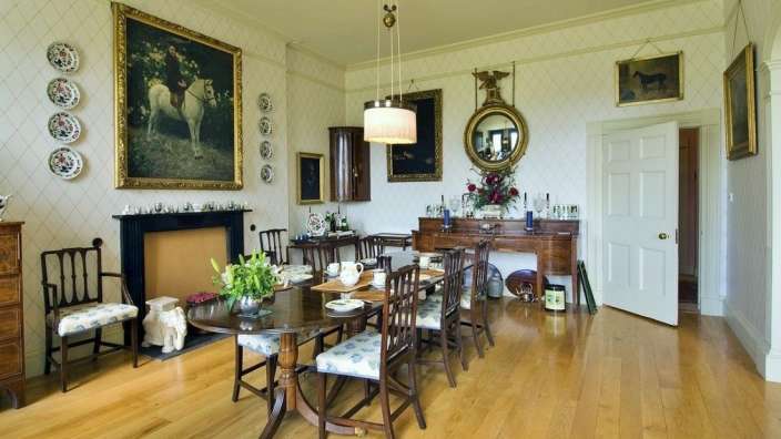 Ein Esszimmer mit einem Tisch und Stühlen und einem Gemälde eines Mannes auf einem Pferd