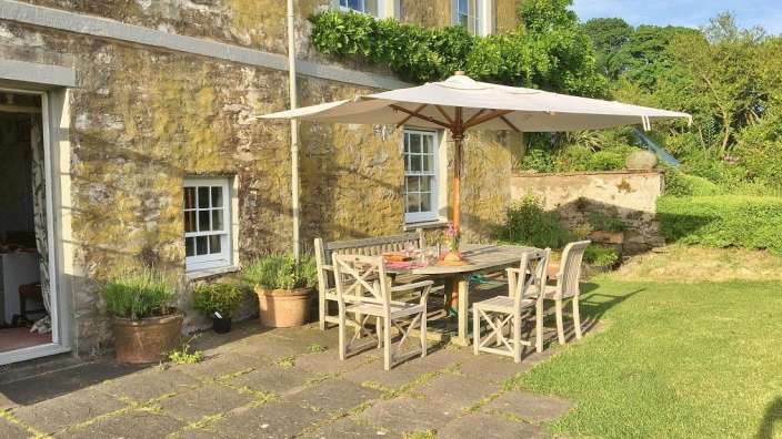 Eine Terrasse mit einem Tisch und Stühlen und einem Regenschirm