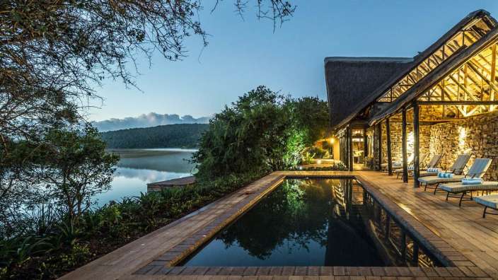 Ein großer Swimmingpool auf einem Holzdeck neben einem See