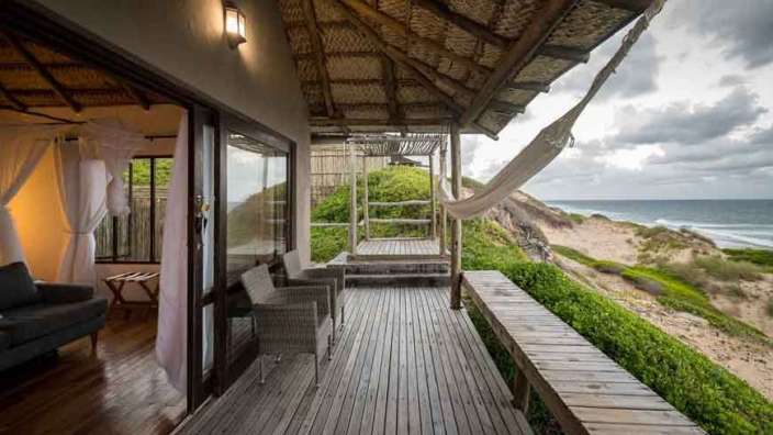 Ein Holzdeck mit einer Hängematte darauf und einem Blick auf den Ozean .