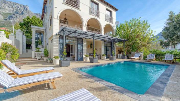 Ein großes weißes Haus mit einem großen Swimmingpool davor