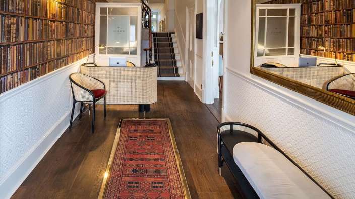 Ein Flur mit Bücherregalen an der Wand und einem roten Teppich