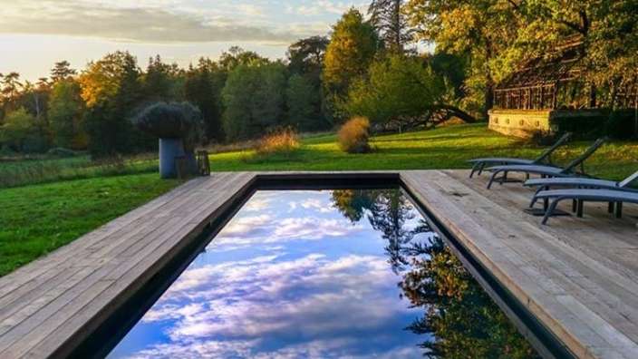 Ein großer Swimmingpool auf einem Holzdeck mit Bäumen im Hintergrund