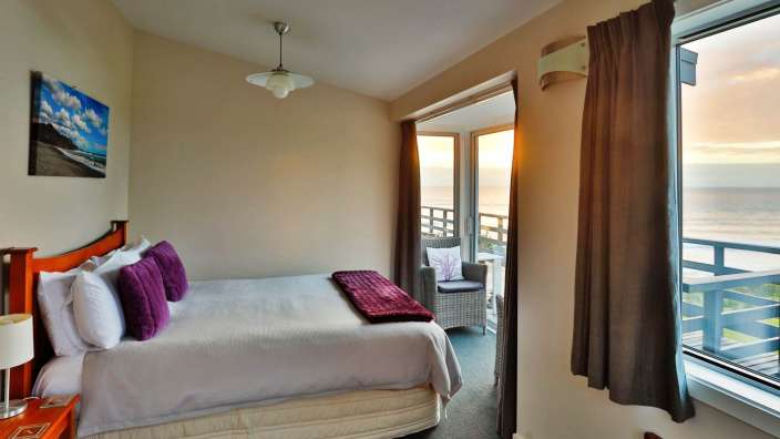 Ein Schlafzimmer mit einem Bett und einem Balkon mit Blick auf das Meer