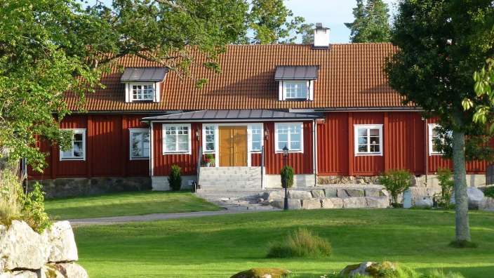 Ein rotes Haus mit weißen Fenstern und einem roten Dach