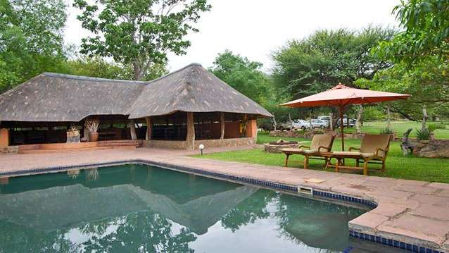 Ein schwimmbad mit einem strohdach und einem roten regenschirm