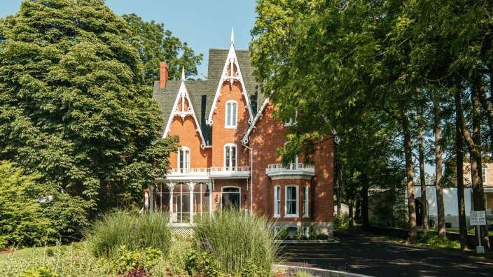 Ein großes rotes Backsteinhaus mit weißen Fenstern und einem grünen Dach