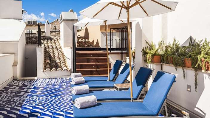 Eine Terrasse mit blauen und weißen Stühlen und einem weißen Regenschirm