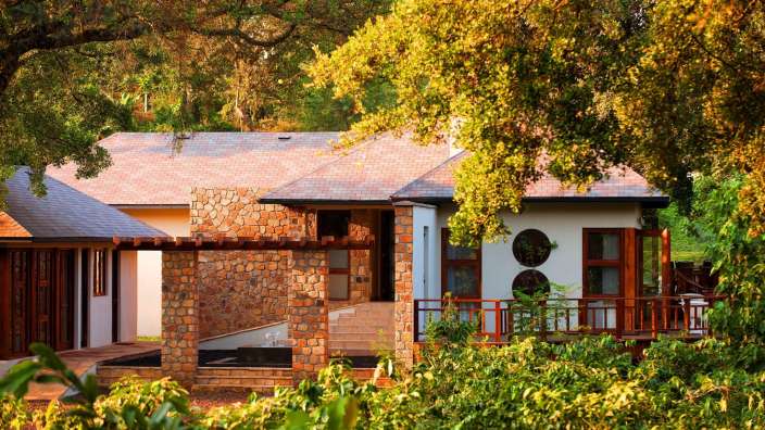 Ein weißes Haus mit einem roten Dach und einer Steinveranda umgeben von Bäumen