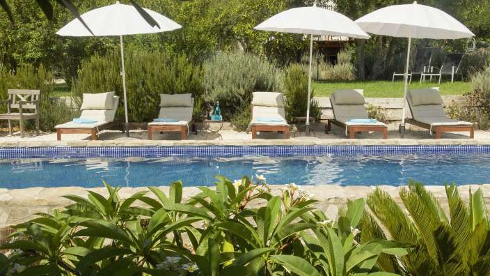 Liegestühle und Sonnenschirme um einen Swimmingpool
