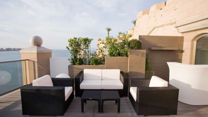 Eine Terrasse mit Möbeln und einem Tisch mit Blick auf das Meer