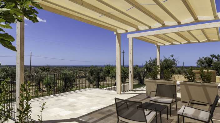 Eine Terrasse mit einem Tisch und Stühlen unter einer Pergola
